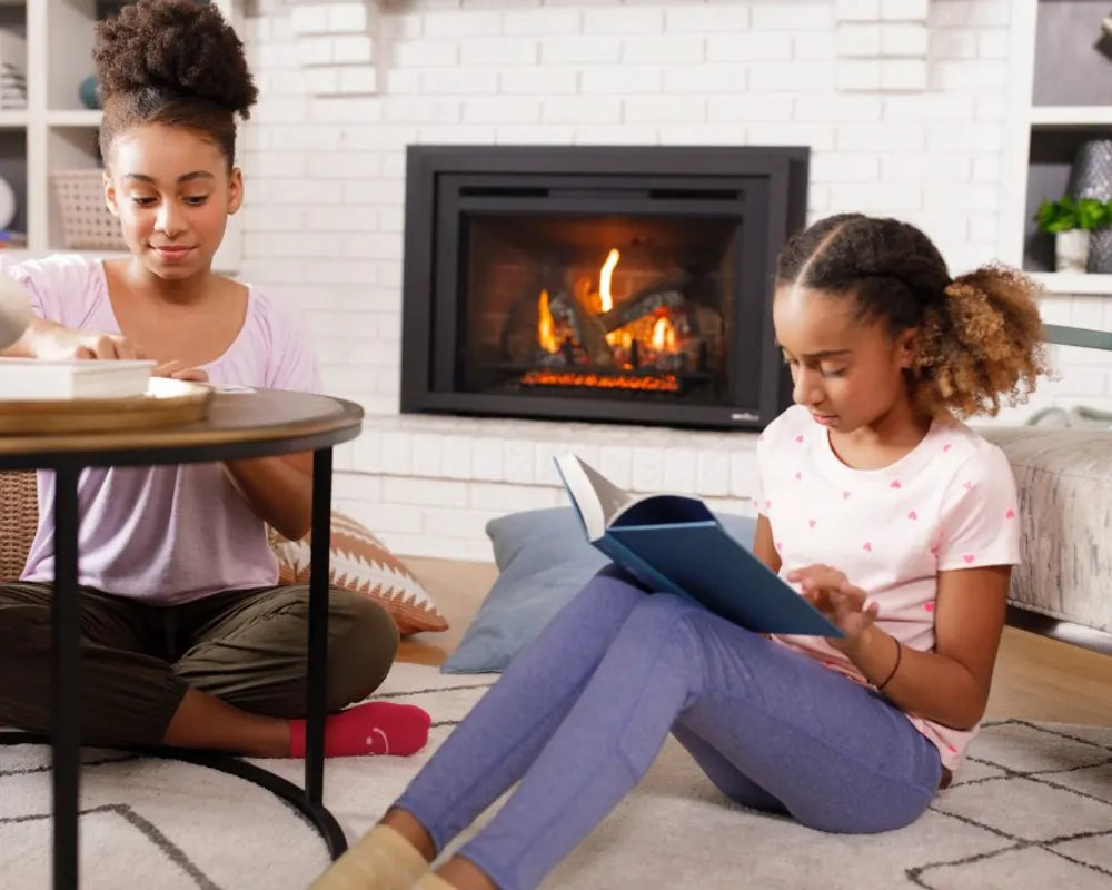 Two kids reading beside a lit Heat & Glo gas insert in a bright family living room
